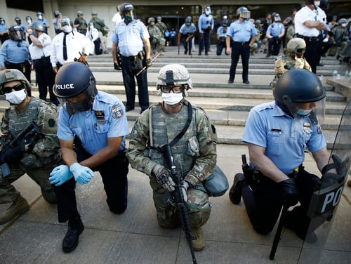 In this June 1, 2020, file photo, Philadelphia police and Pennsylvania National Guard take a knee at the suggestion of Philadelphia Police Deputy Commissioner Melvin Singleton, unseen, outside Philadelphia Police headquarters in Philadelphia, during a march calling for justice over the death of George Floyd. (Matt Rourke/AP)