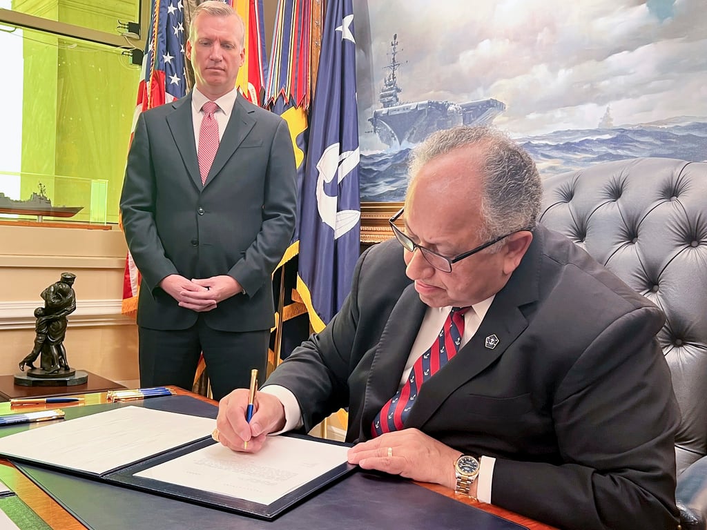 Navy Secretary Carlos Del Toro signs documents exonerating 256 Black sailors who were unjustly court-martialed in 1944 after the horrific Port Chicago explosion in California, as Navy Under Secretary Erik Raven looks on, Wednesday, July 17, 2024, at the Pentagon in Washington. (Tara Copp/AP)