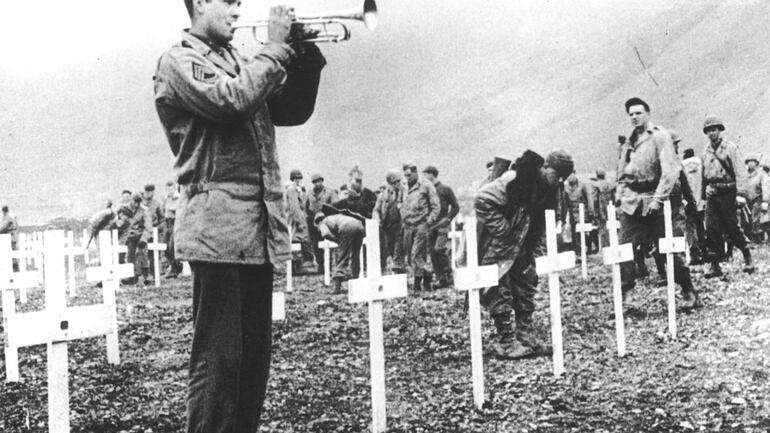 In this August 1943 file photo, a bugler sounds taps during a memorial service while a group of GIs visit the graves of comrades who fell in the reconquest of Attu Island, part of the Aleutian Islands of Alaska. May 30, 2018 will mark the 75th anniversary of American forces recapturing Attu Island in Alaska's Aleutian chain from Japanese forces. It was the only World War II battle fought on North American soil. (AP)