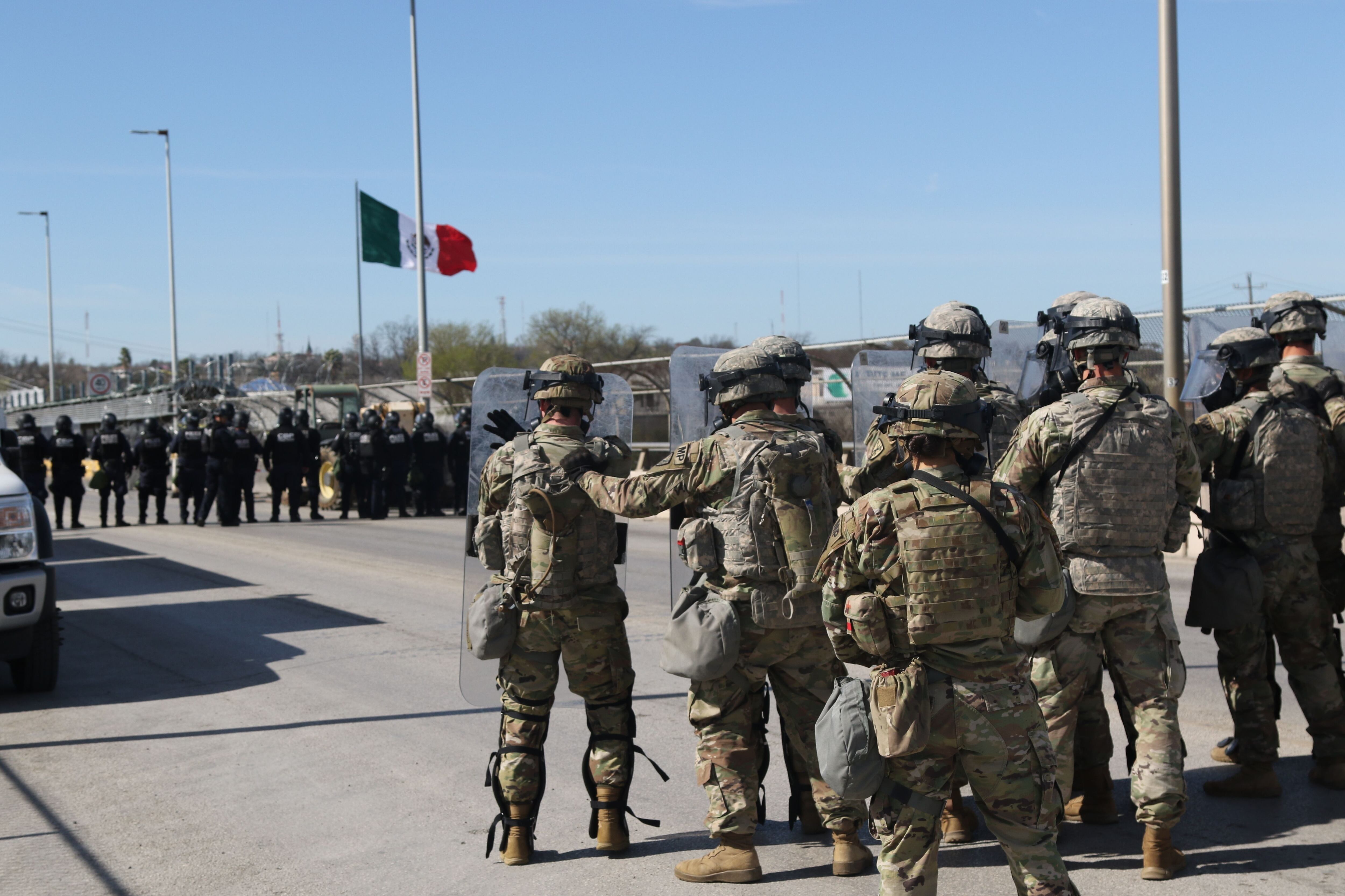 Three migrants who had managed to evade National Guard and cross the Rio  Grande onto U.S. territory wait for Border Patrol along a wall set back  from the geographical border, in El