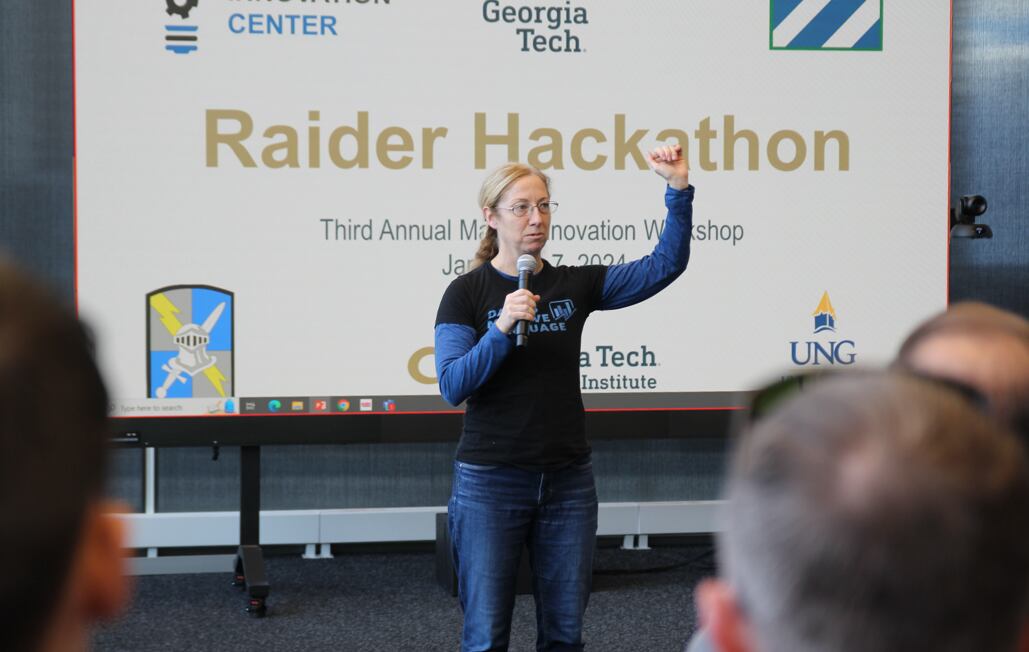 A woman in civilian clothing, wearing a shirt that says, "Data is my love language," stands with a microphone.