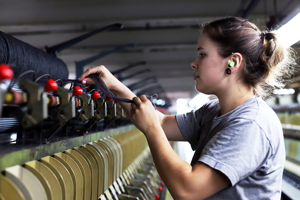 Spinning operator Sara Colburn pulls fabric off the spinning frame inside the mill on July 3, 2019, at American Woolen Company Inc., in Stafford Springs, Conn.