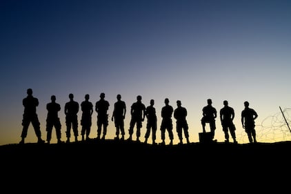 Airmen of the 332nd Air Expeditionary Wing pose for a group photo during sunrise after their shift at an undisclosed location on Aug. 15, 2020.