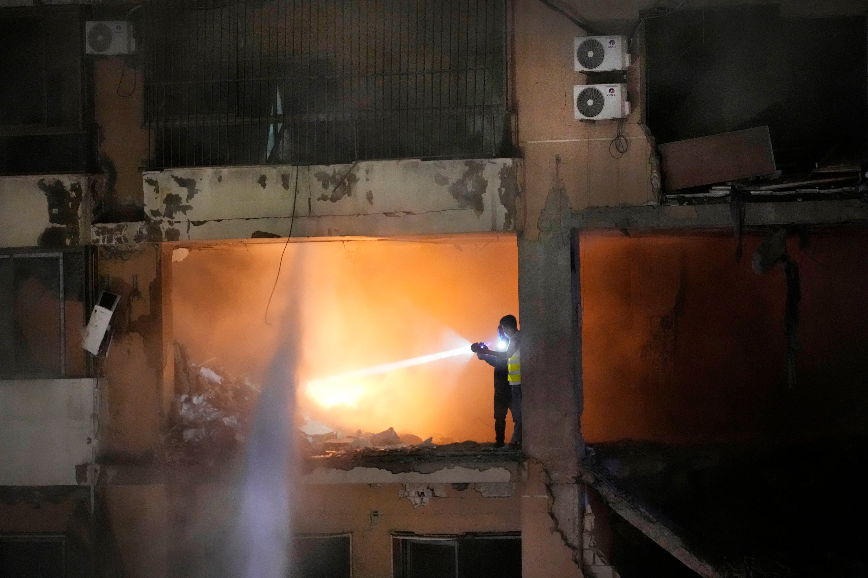 Civil defense workers search for survivors inside an apartment following a massive explosion in the southern suburb of Beirut, Lebanon, Tuesday, Jan. 2, 2024.