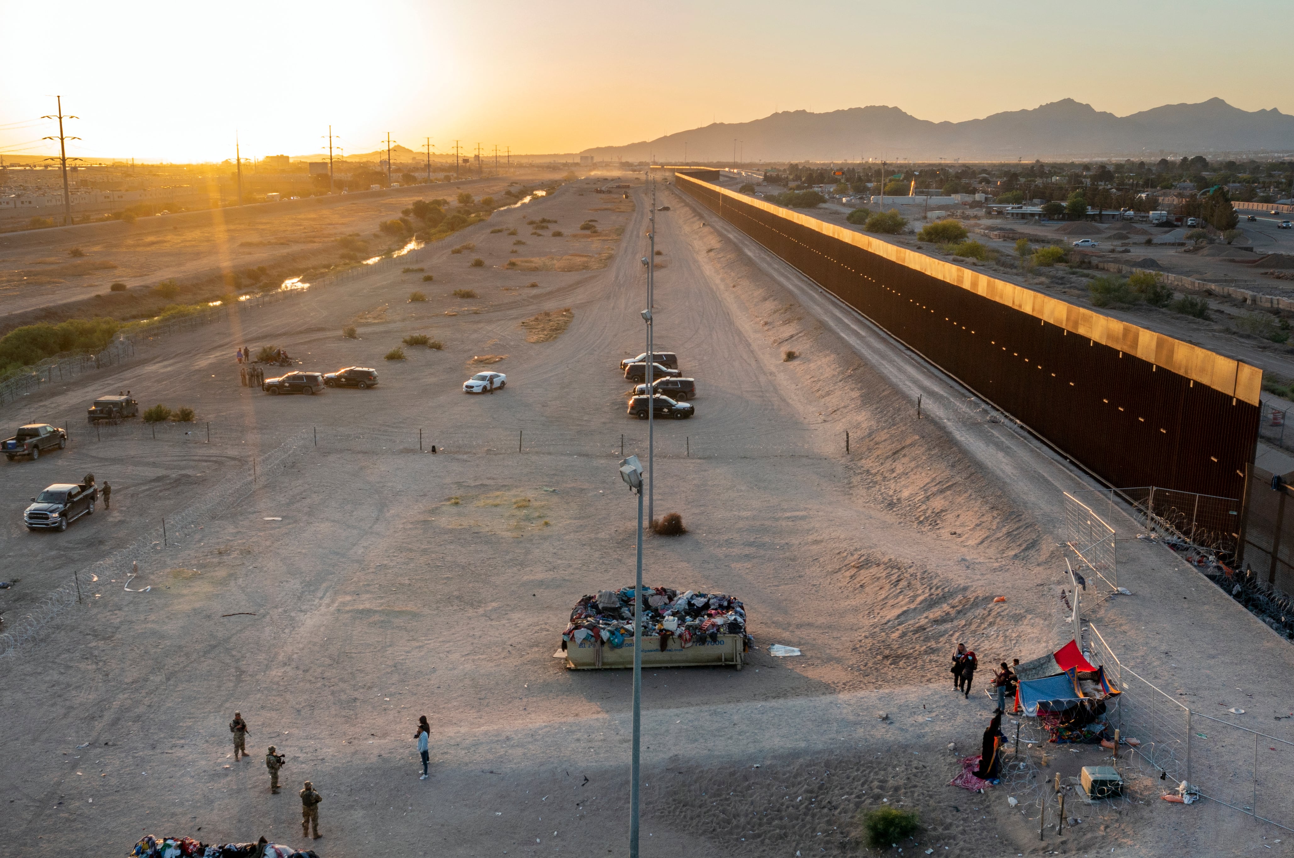 A small group of migrants, bottom right, are pictured while camping outside a gate in the border fence in El Paso, Texas, Friday, May 12, 2023.