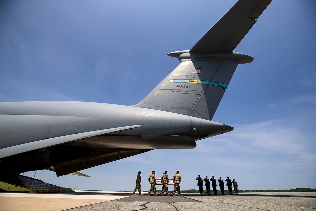 Officers salute as an Army carry team moves a transfer case containing the remains of Army Sgt. 1st Class Elliott J. Robbins at Dover Air Force Base, Del., Tuesday, July 2, 2019.