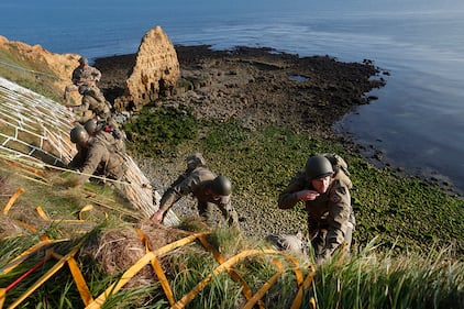 Soldiers from the U.S. 75th Ranger Regiment, in period dress, climb the cliff of Pointe-du-Hoc