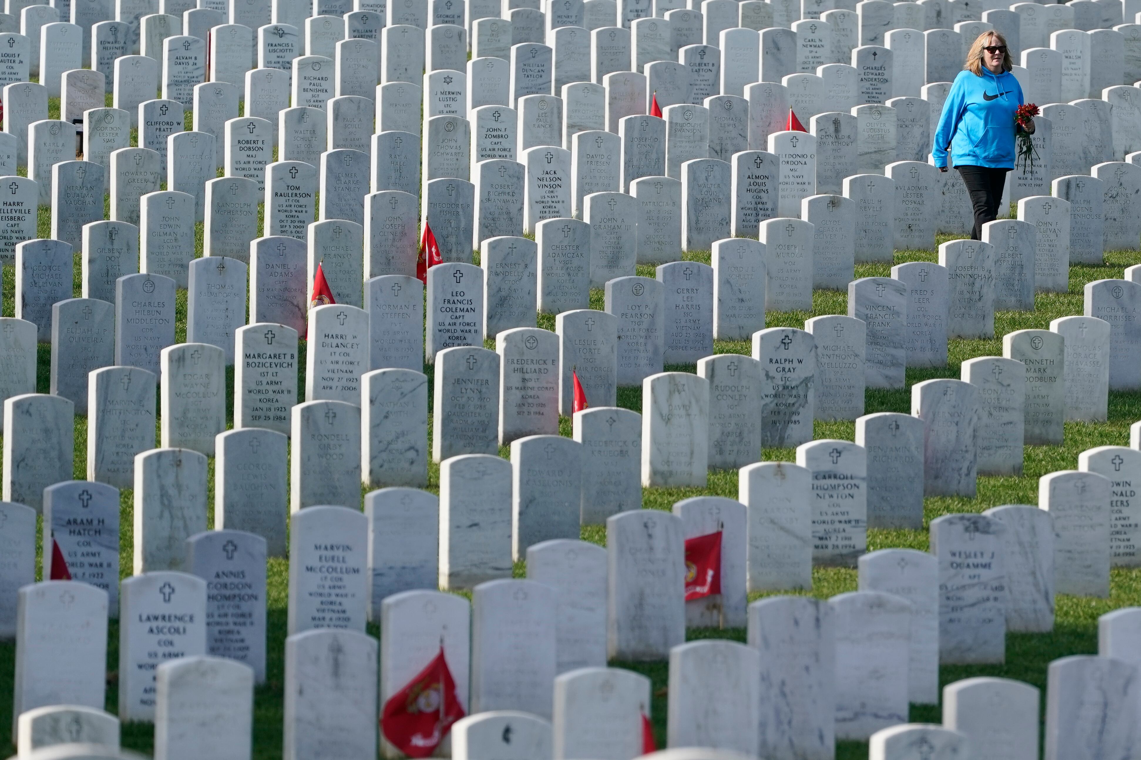 A visitor walks among headstones in Section 60 at Arlington National Cemetery, Nov. 11, 2021, in Arlington, Va. Section 60 is where the men and women who died in America's most recent wars, especially Iraq and Afghanistan, are buried.