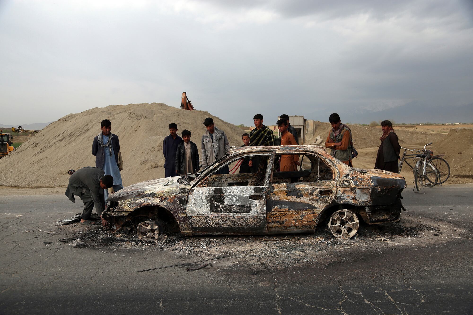 In this April 9, 2019, file photo, Afghans watch a civilian vehicle burnt after being shot by U.S. forces following an attack near the Bagram Air Base, north of Kabul, Afghanistan.