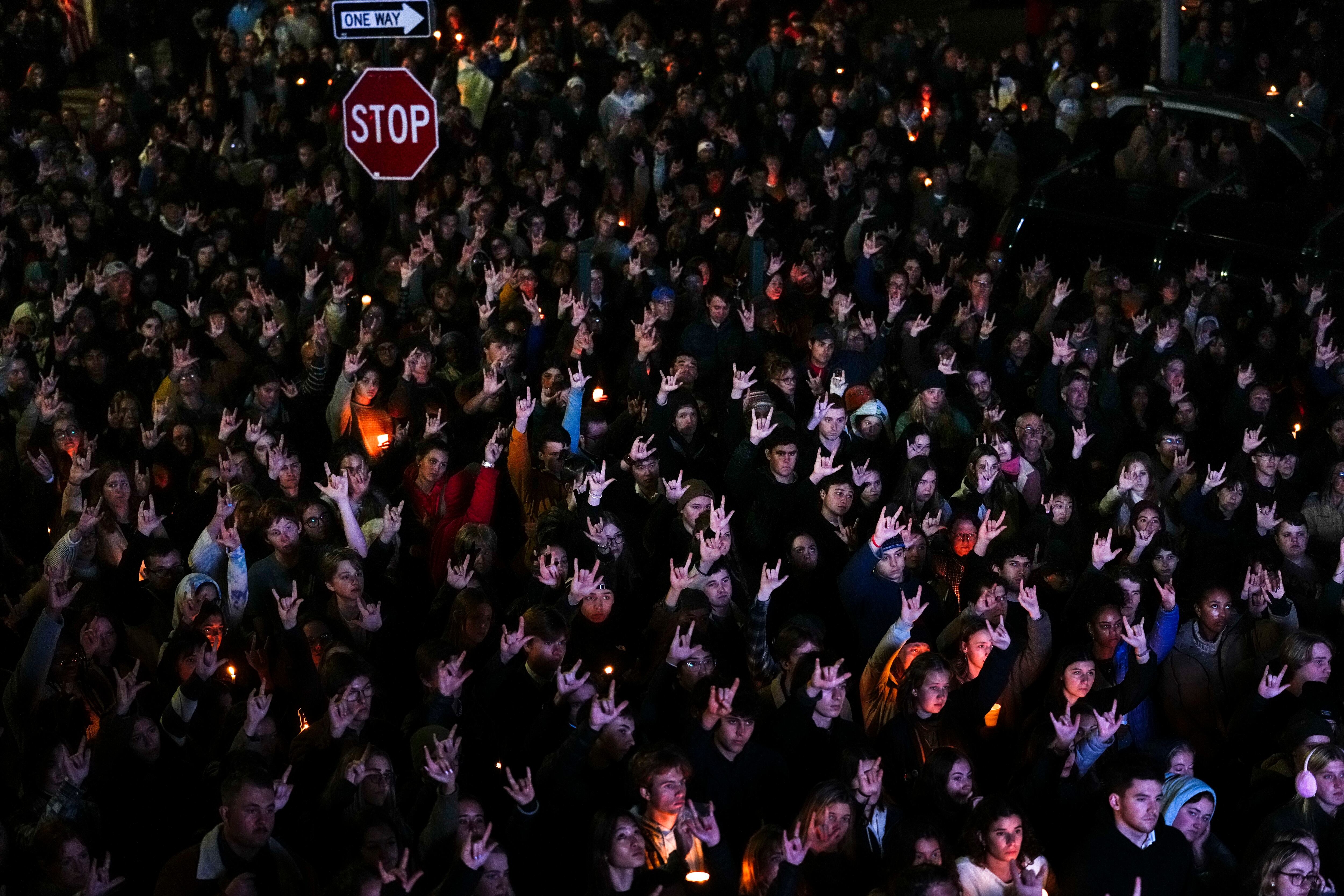 People sign "I love you," while gathered at a vigil for the victims of mass shootings days earlier, Sunday, Oct. 29, 2023, outside the Basilica of Saints Peter and Paul in Lewiston, Maine.