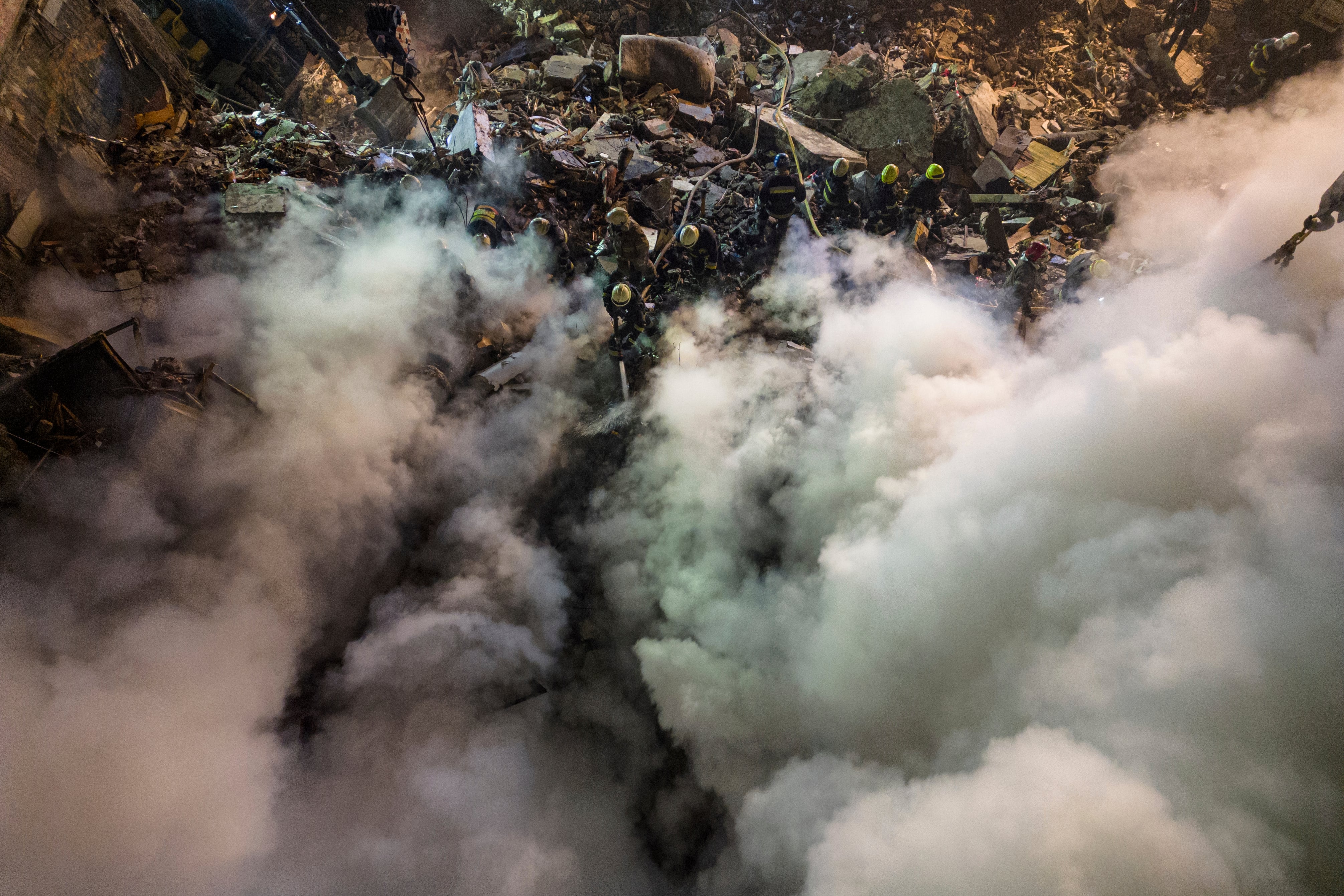 Emergency workers clear the rubble after a Russian rocket hit a multistory building leaving many people under debris in the southeastern city of Dnipro, Ukraine, Saturday, Jan. 14, 2023.