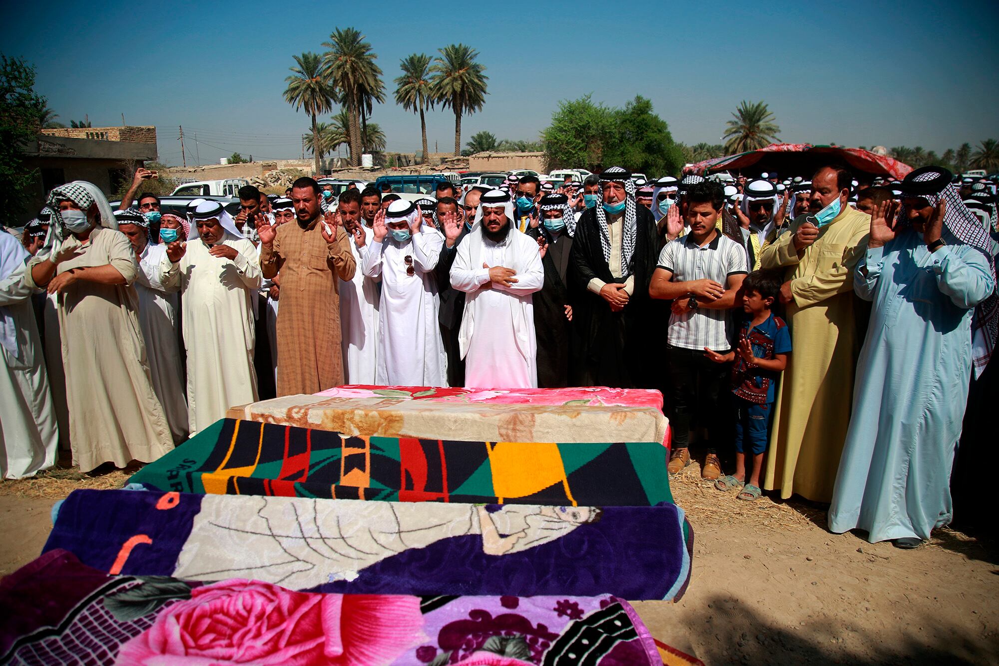 Mourners pray over the coffins of civilians killed by a Katyusha rocket attack near the international airport in Baghdad, Iraq, Tuesday, Sept. 29, 2020.