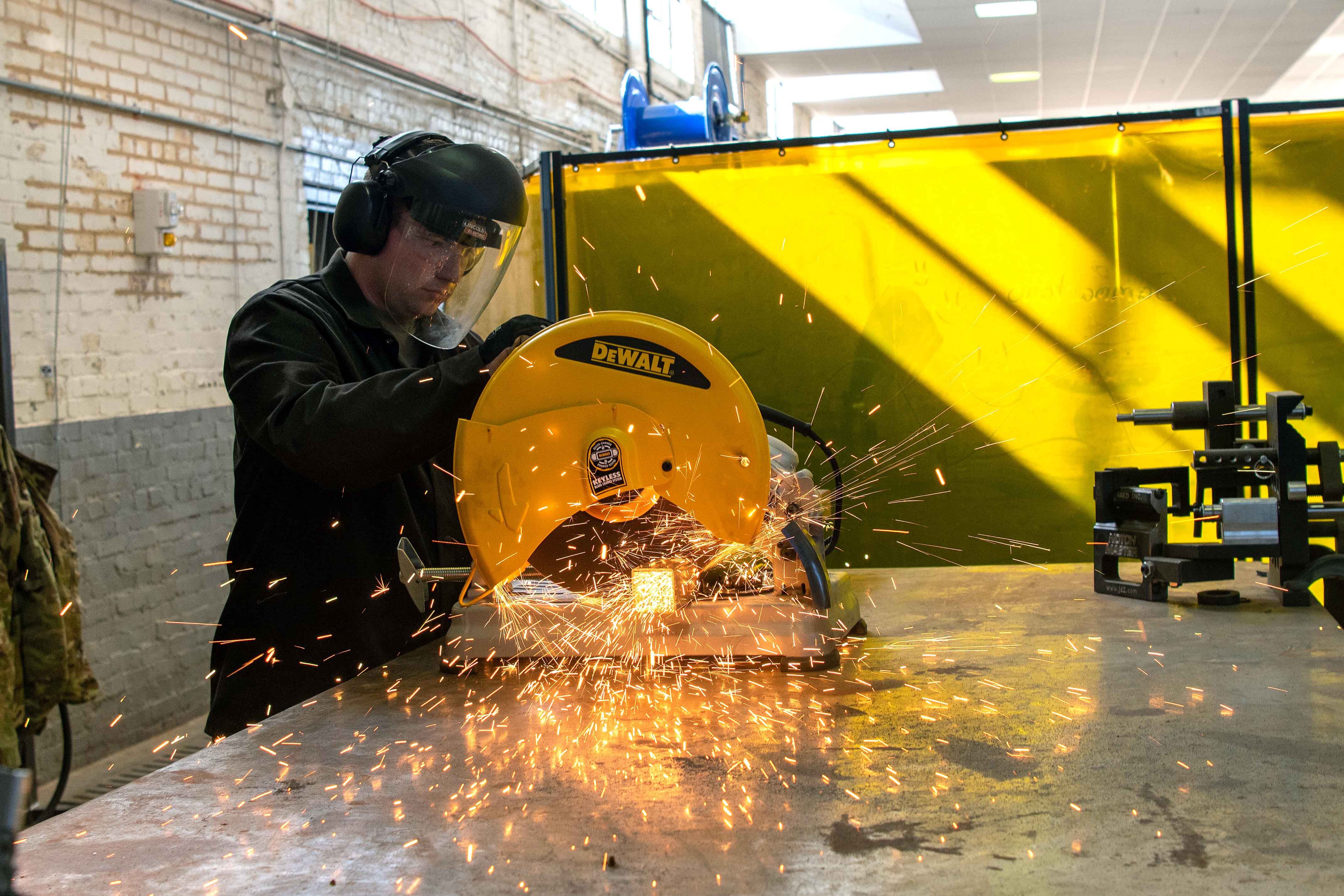 Tech. Sgt. Ryan Rinn, 22nd Air Refueling Wing Innovation Lab noncommissioned officer in charge, uses a power saw to cut a metal plank Sept. 1, 2022, at McConnell Air Force Base, Kan. All Airmen are encouraged to use the lab’s equipment to make various items like plaques, racked and 3D-printed models. (Airman William Lunn/Air Force)