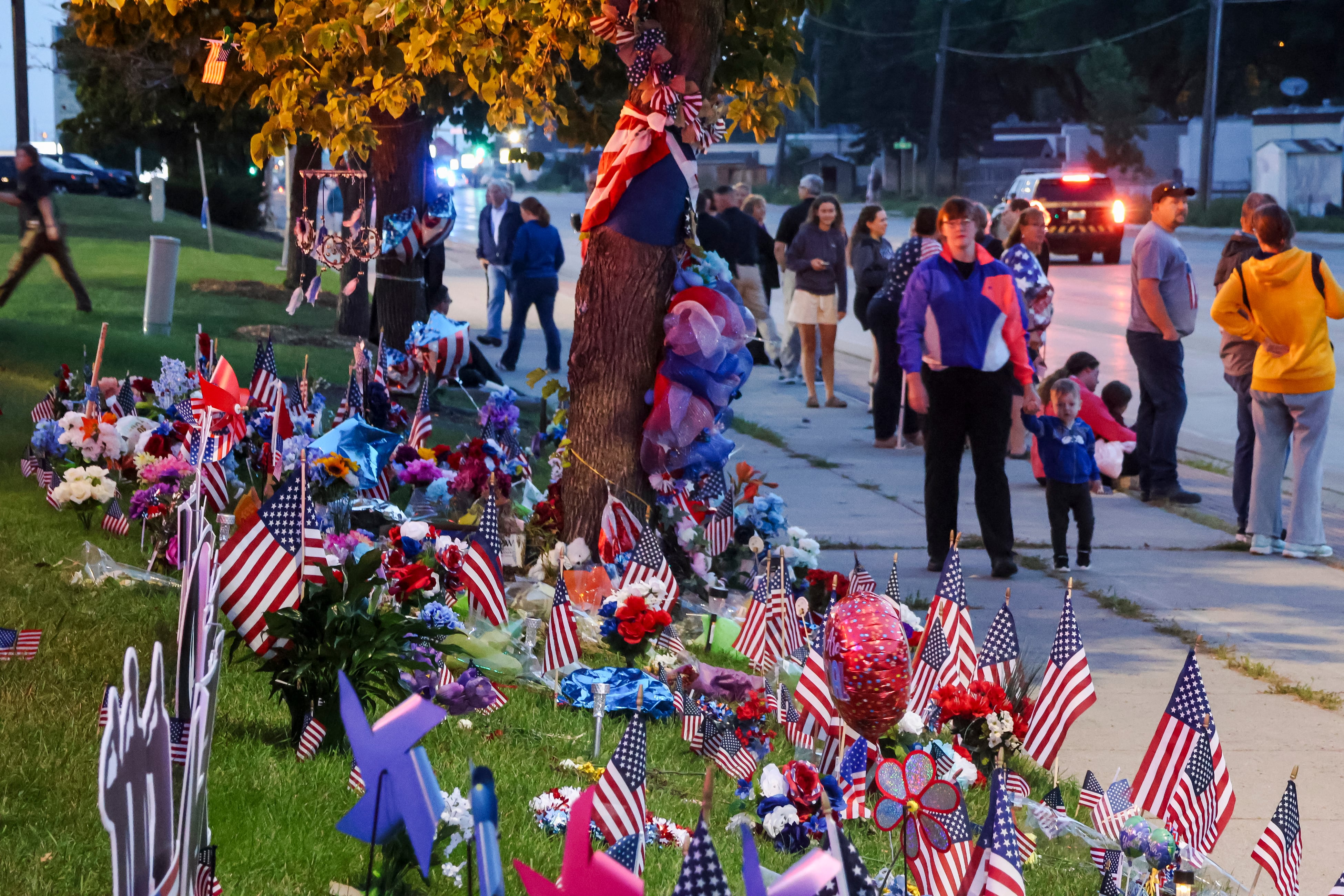 People gather during an escort of the late Fargo Police Officer Jake Wallin to his funeral near the intersection in Fargo, N.D., where he was fatally shot last week on Saturday, July 22. 2023.