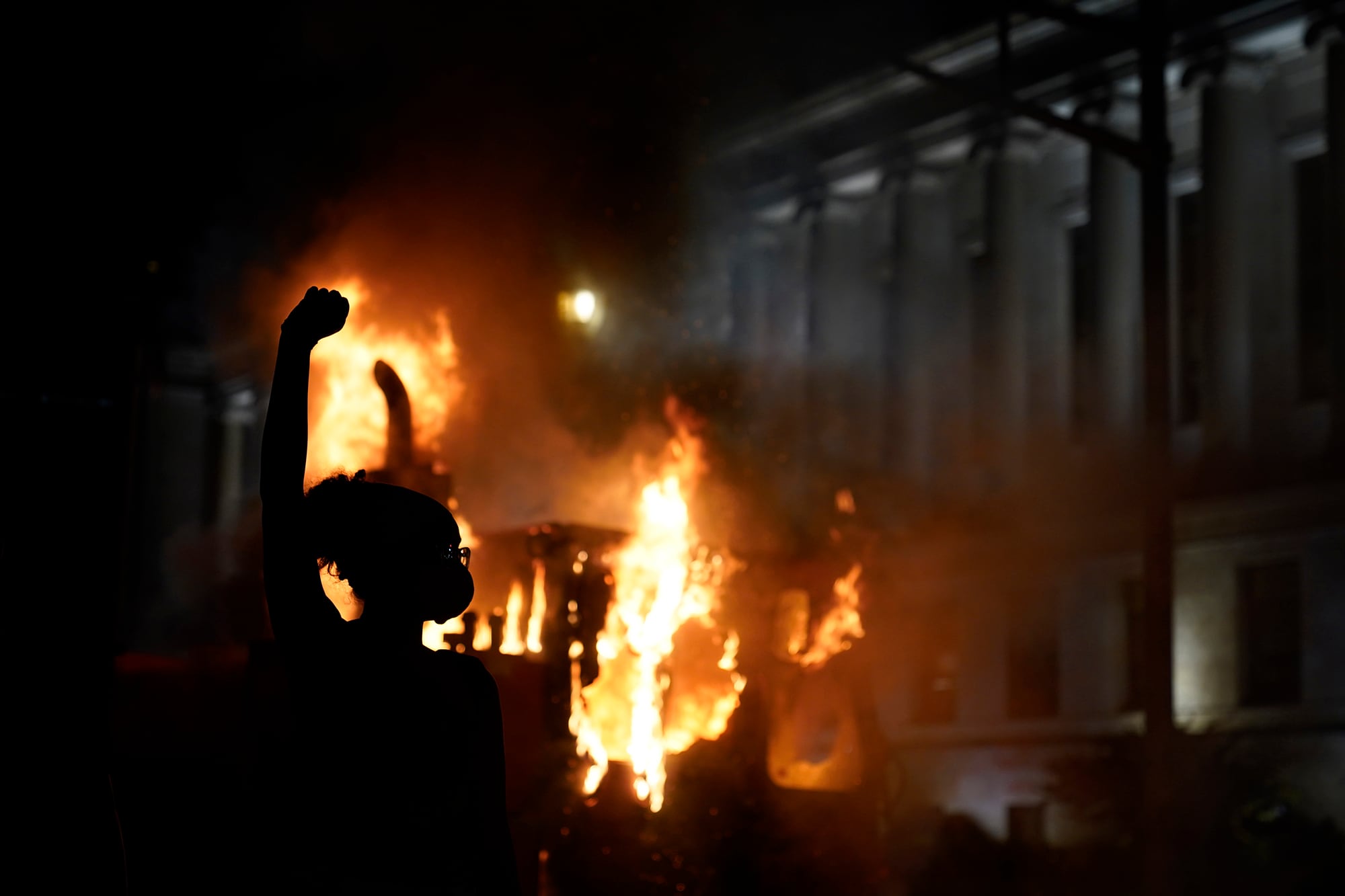 A protester stands in a cloud of tear gas near a burning garbage truck outside the Kenosha County Courthouse, late Monday, Aug. 24, 2020, in Kenosha, Wis.