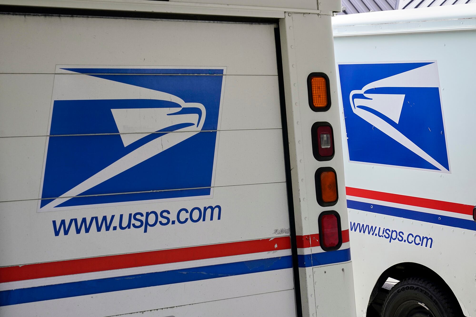 In this Aug. 18, 2020, file photo, mail delivery vehicles are parked outside a post office in Boys Town, Neb.