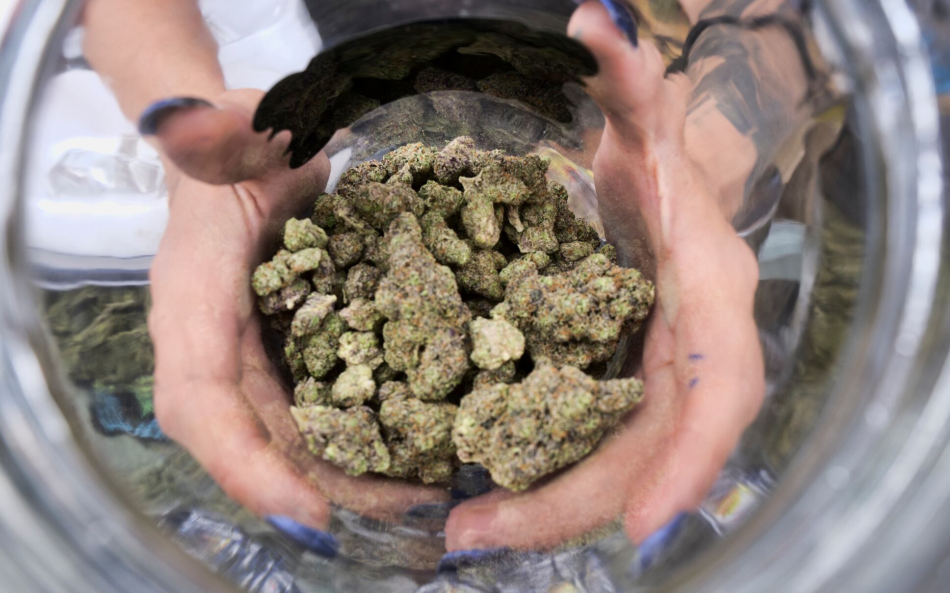 In this April 21, 2018, file photo a budtender displays a jar of cannabis at the High Times 420 SoCal Cannabis Cup in San Bernardino, Calif.