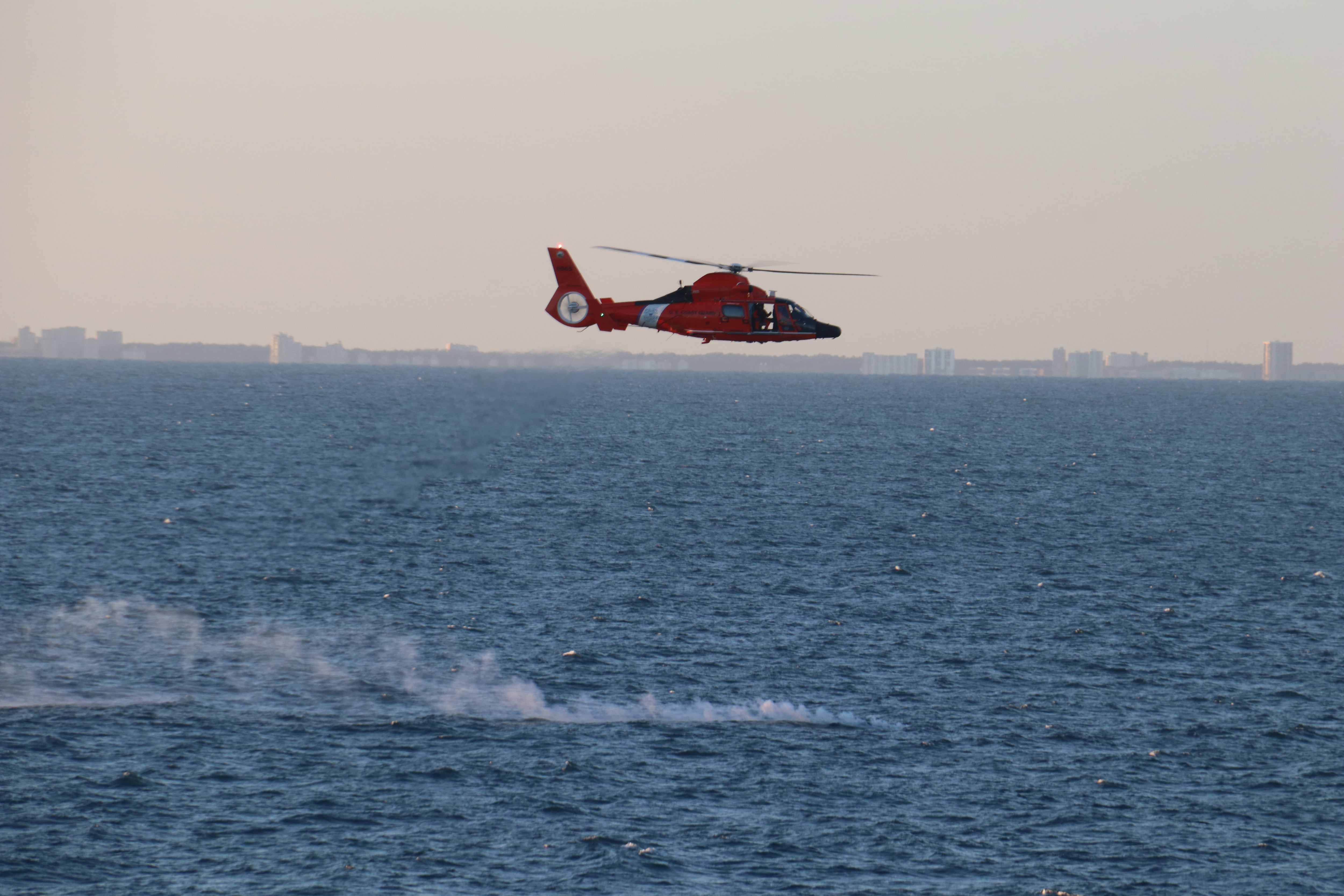 A Coast Guard helicopter flies over a debris field during recovery efforts of a high-altitude surveillance balloon Feb. 4, 2023.