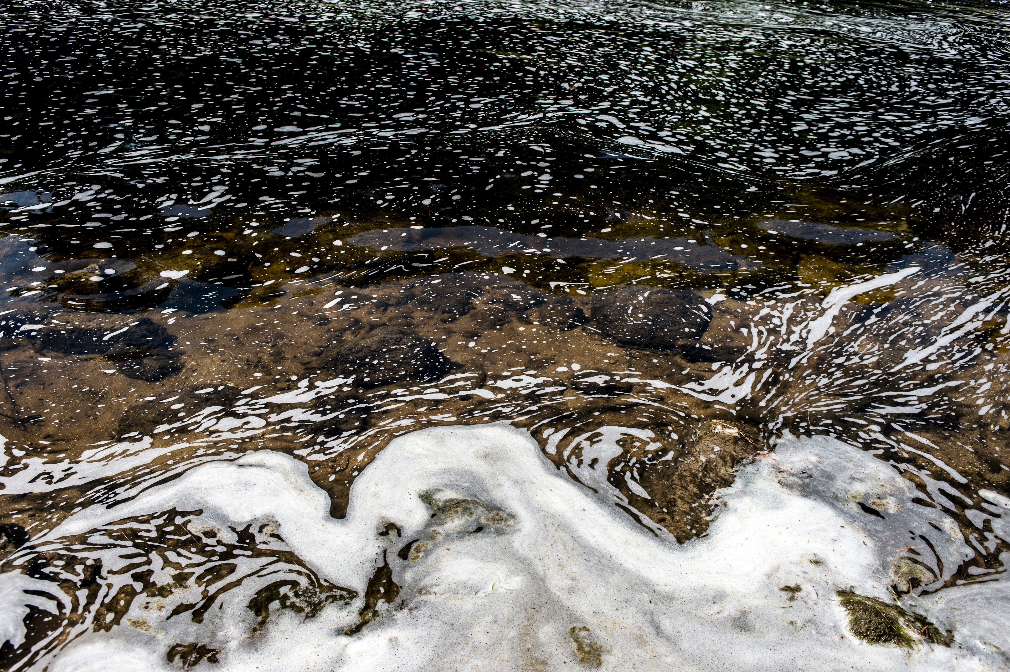 PFAS foam gathers at the the Van Etten Creek dam in Oscoda Township, Mich., near Wurtsmith Air Force Base on June 7, 2018.