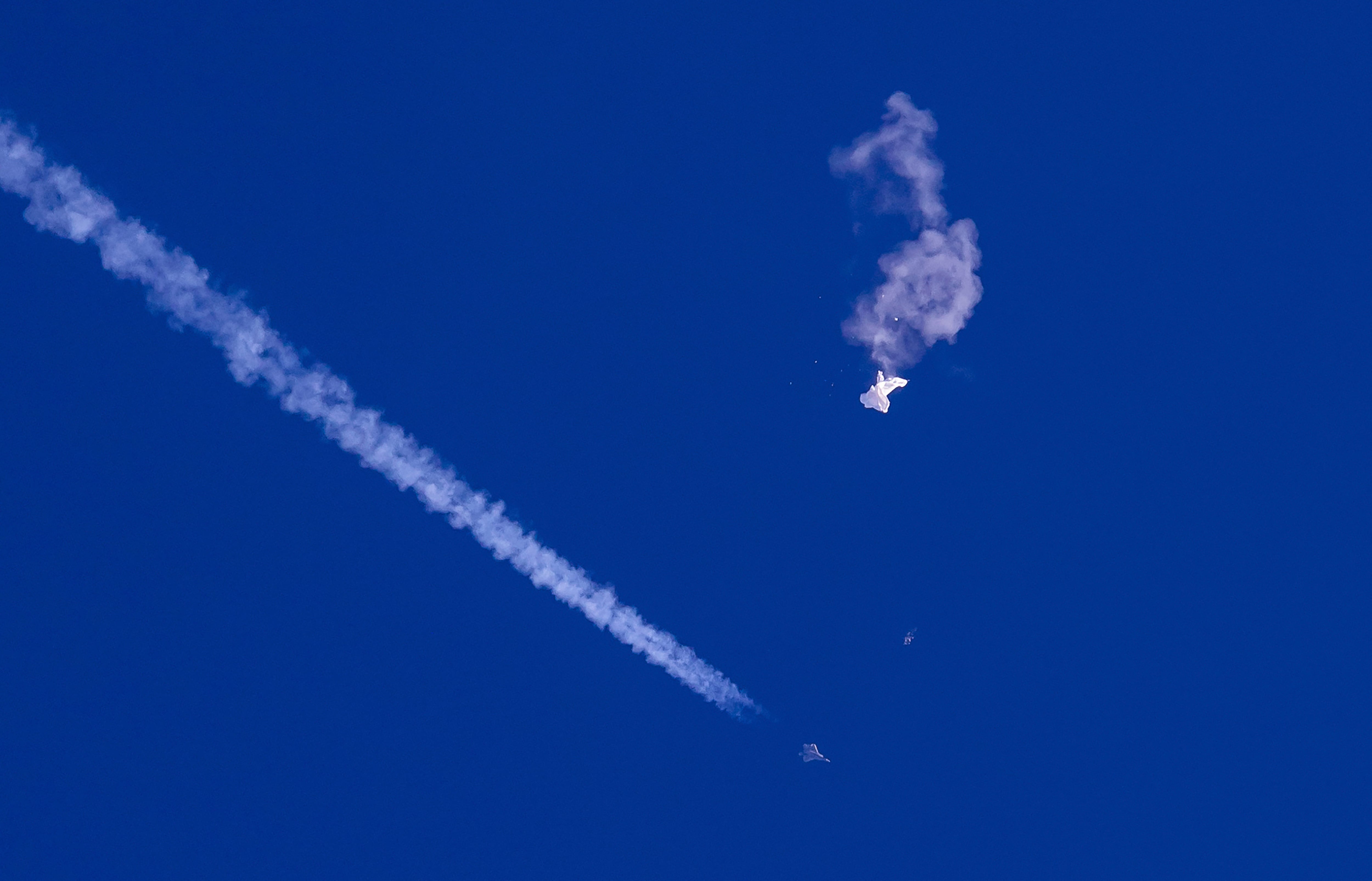 A fighter jet flies past the remnants of a large balloon after it was shot down above the Atlantic Ocean, just off the coast of South Carolina near Myrtle Beach, Feb. 4, 2023.