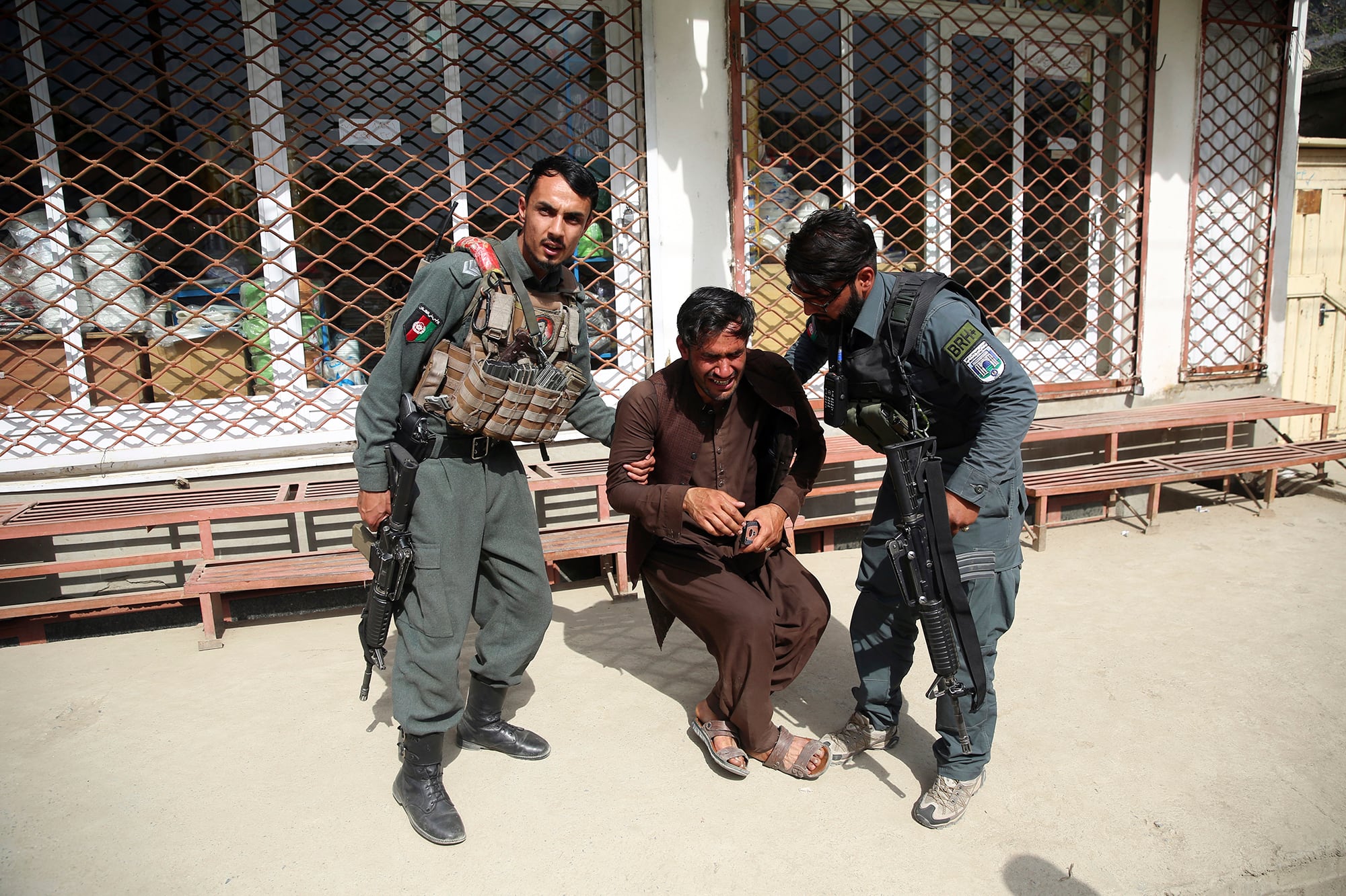 Afghan policemen comfort a man after an attack on a maternity hospital, in Kabul, Afghanistan, Tuesday, May 12, 2020.