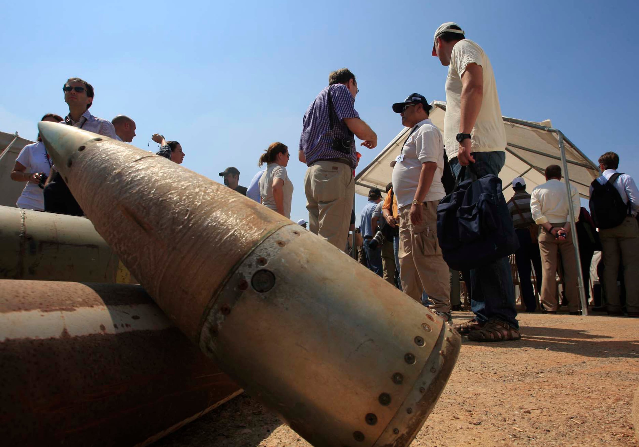 Activists and international delegations stand next to cluster bomb units, during a visit to a Lebanese military base at the opening of the Second Meeting of States Parties to the Convention on Cluster Munitions, in the southern town of Nabatiyeh, Lebanon, Sept. 12, 2011.