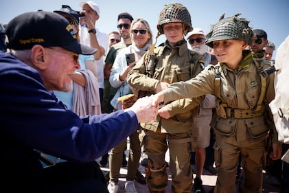 A U.S. veteran shakes hands with a World War II enthusiasts during a gathering in preparation of the 79th D-Day anniversary in Sainte-Mere-Eglise, Normandy, France, Sunday, June 4, 2023.